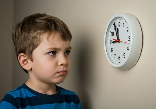 Child looking confused at an analog clock on the wall