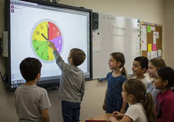 Children in a classroom setting interactive whiteboard clock.