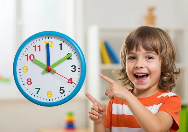Kindergartener learning time happily with an analog clock