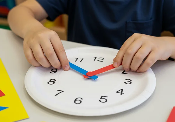 Child making a paper plate clock for time learning